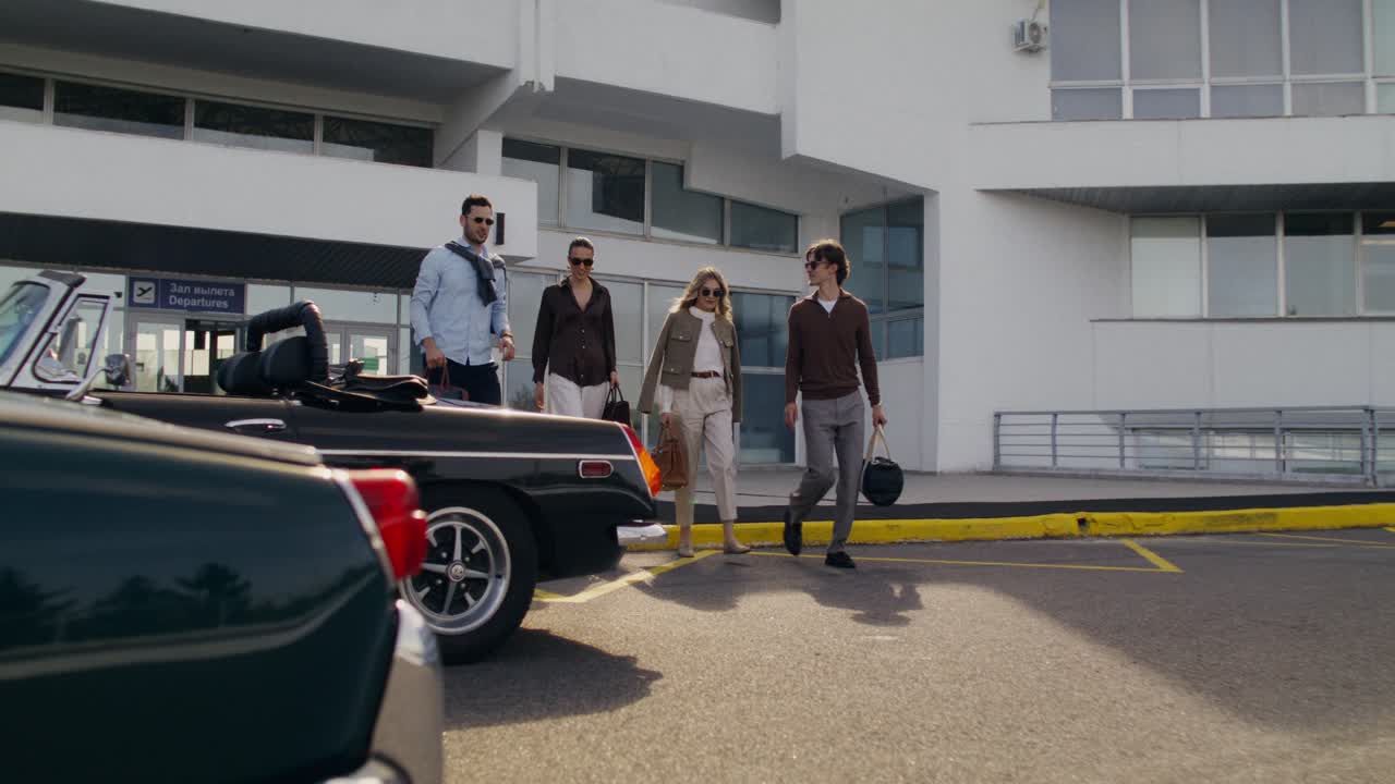 Group of friends at the airport loading a vintage car