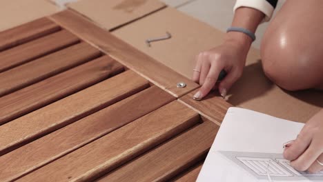 hands assembling wooden furniture using screws and instructions. indoor setting with natural lighting and close-up shots