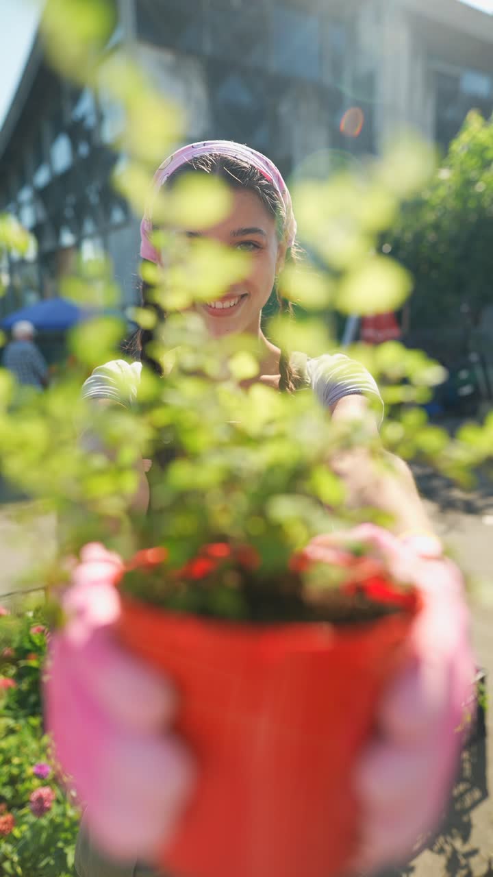 una mujer joven sosteniendo una planta en una olla en un centro de jardinería