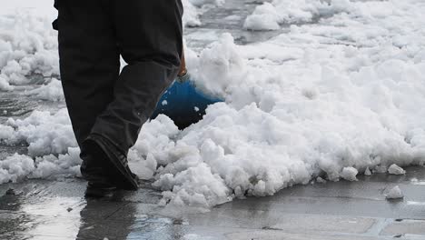 person shoveling snow on a wet city street