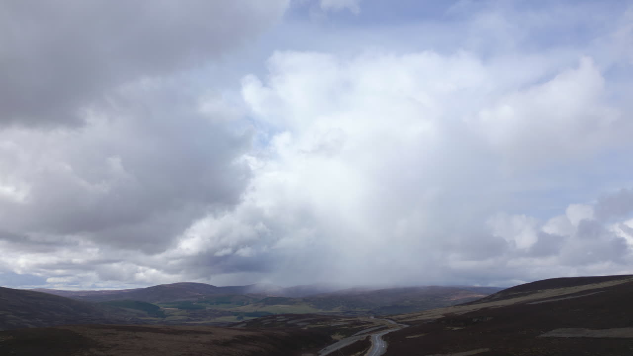 lento descenso aéreo sobre los cairngorms, nube de lluvia en el fondo, escocia