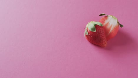 video of halved strawberry with copy space over pink background