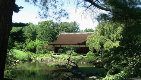 long shot of a traditional japanese house with surrounding garden and pond