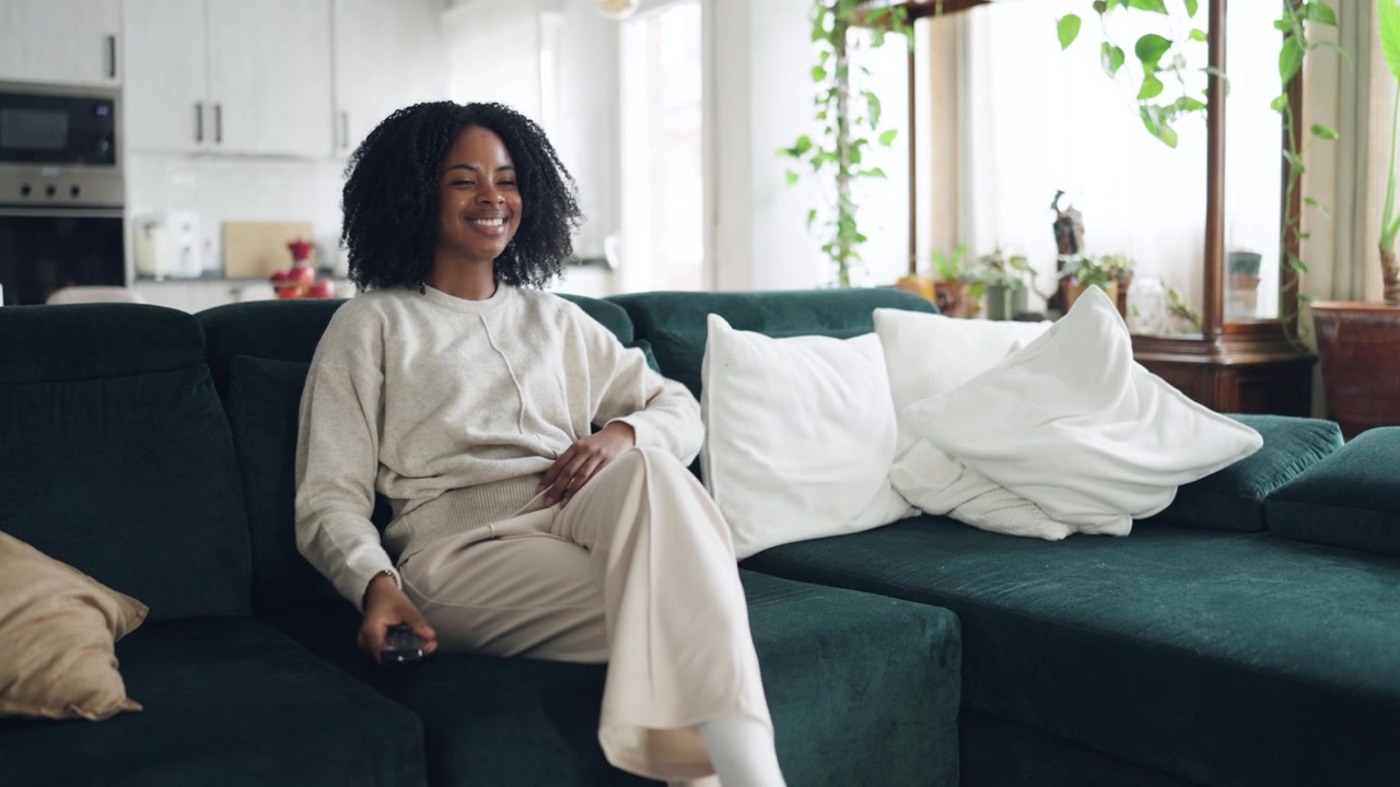 Happy African American Woman Watching TV on Couch at Home
