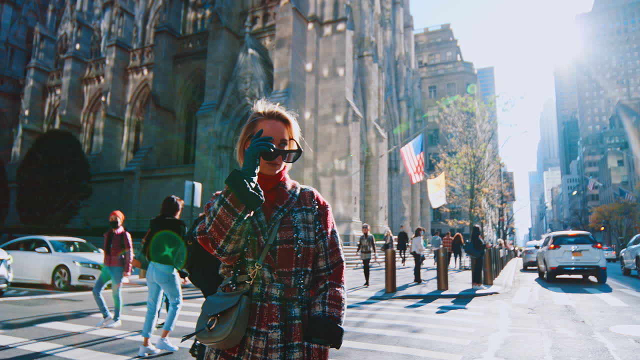 New York, USA, 25 ottobre 2025: Ritratto di profilo di donna bionda su una strada di Manhattan. Primo piano di profilo di donna in dolcevita rosso e cappotto a quadri con sfondo di edifici cittadini
