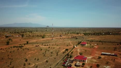Vista-Aérea-Panorámica-De-Drones-De-Un-área-En-Uganda-Con-Casas-Y-Una-Antena-De-Telecomunicaciones-En-Un-Día-Soleado