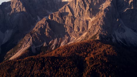 Tiro-Inclinado-Hacia-Arriba,-Bosques-De-Color-Rojo-Y-Montañas-De-Los-Alpes-Dolomitas-En-Italia-Durante-La-Iluminación-De-La-Puesta-De-Sol-Dorada---Punta-Tre-Scarperi-En-El-Parque-Natural-Tre-Cime