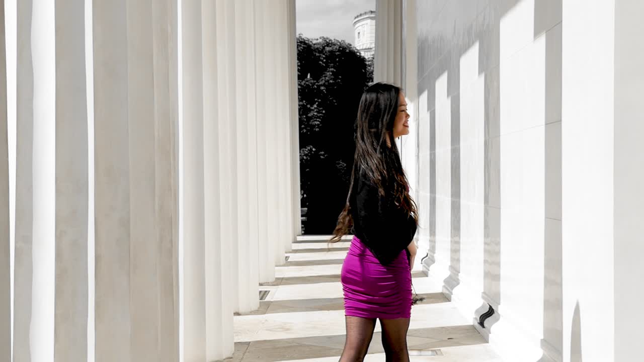 활기찬 옷을 입은 젊은 여성이  기둥 사이에 미소 짓고, 비엔나의 스타트파크에서 이 나는 날