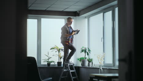 man installing a security camera on the ceiling of an office