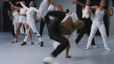 multi-ethnic group of fit male and female modern dancers practicing dance routine