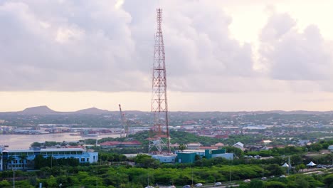 una gran torre de telecomunicaciones se erige en contra de las ciudades de curaçao y el cielo nublado.