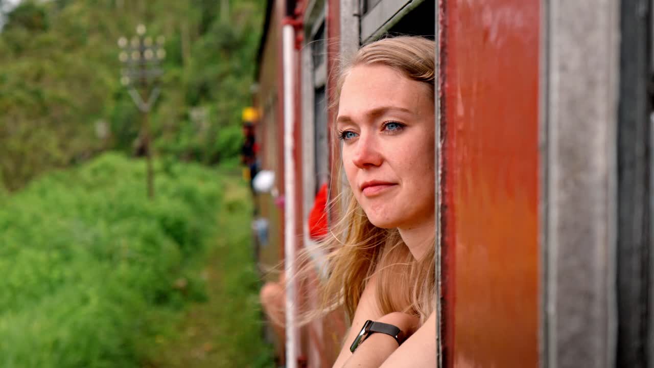 A woman sits by the window of the iconic Ella to Kandy train in Sri Lanka, peacefully gazing at the passing landscape filled with tea plantations, misty hills, and tropical vegetation.