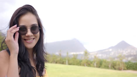 A-young-biracial-woman-adjusts-her-sunglasses-outdoors-in-the-backyard-at-home,-copy-space