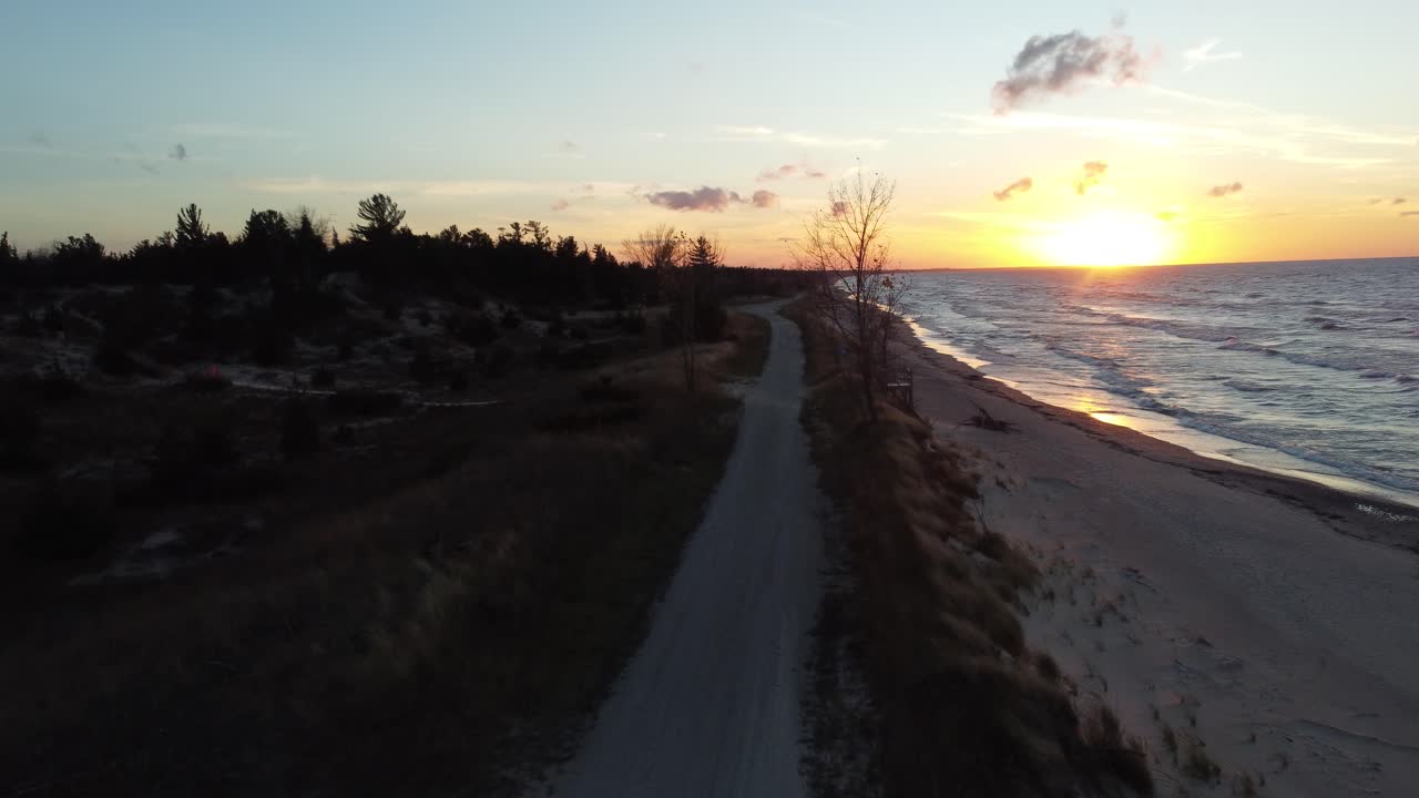 puesta de sol detrás del mar y la playa, con la cámara volando hacia el sol