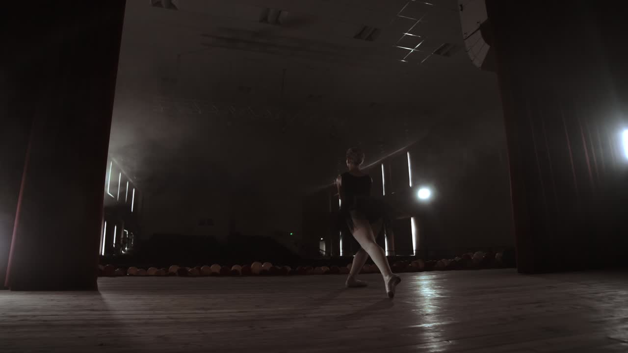 movimiento lento: prima ballet en un vestido negro realiza rotaciones y baila movimientos graciosos ensayando un programa en solitario. la cámara se mueve en gimbal