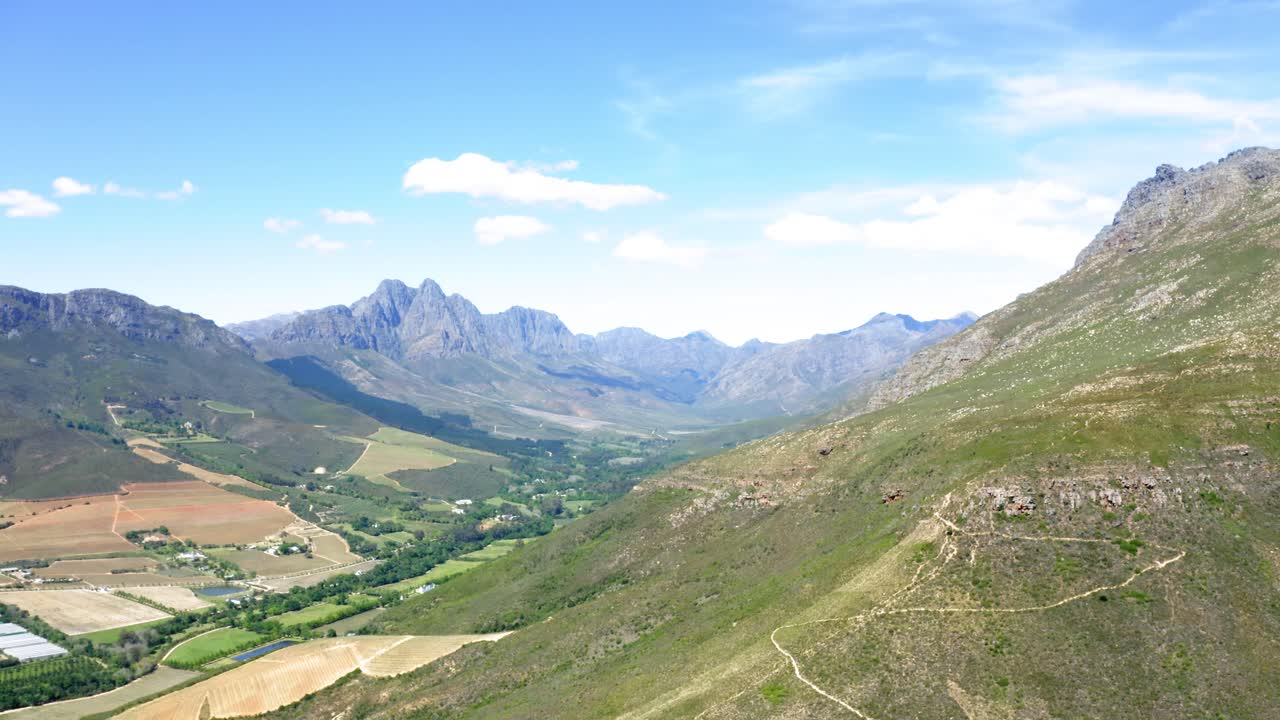 drone aéreo, ladera verde de la montaña con un sendero empinado desde el valle de tierras agrícolas y bosques, stellenbosch, holanda hottentots, jonkershoek