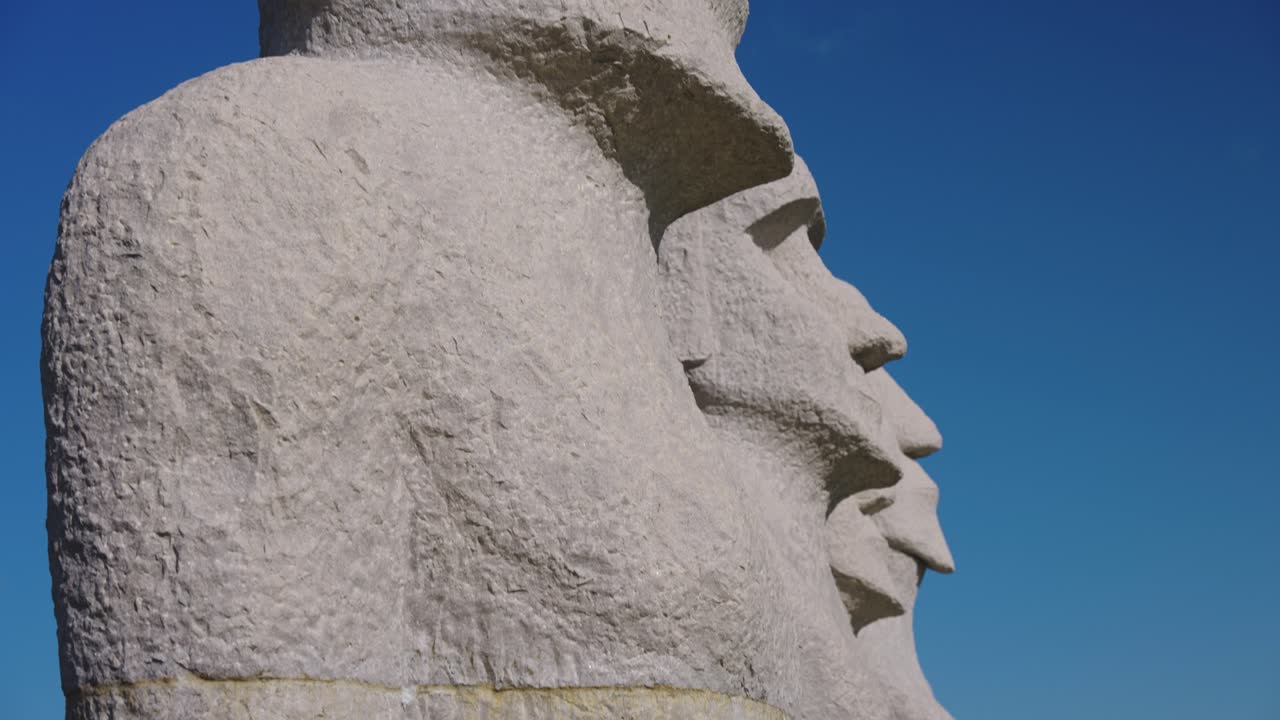 Primo piano dei volti delle statue Moai, sfondo cielo blu.
