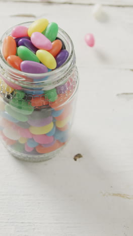 video of multi coloured jelly sweets in jar over white rustic background