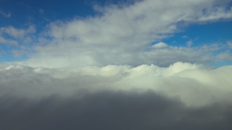 An immersive pilot’s view from cockpit while flying through a dreamy cloudscape of stratus ethereal clouds in a blue sky at the blue hour