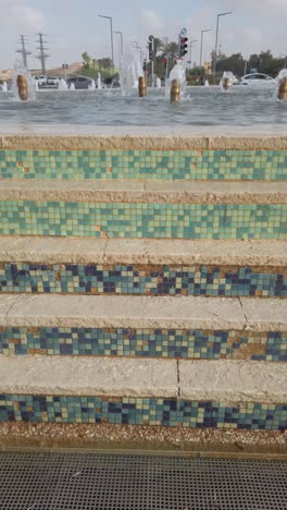 Water in waterfall fountain at city street. Vertical video frame.