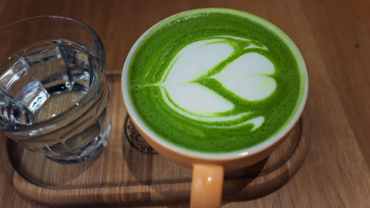 Close up of a matcha latte on a wooden tray at a cafe
