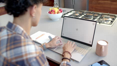 using laptop and typing, teenage boy working from home at kitchen counter, copy space