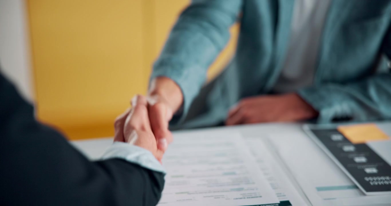 Business Professionals Shaking Hands Over Documents in Office