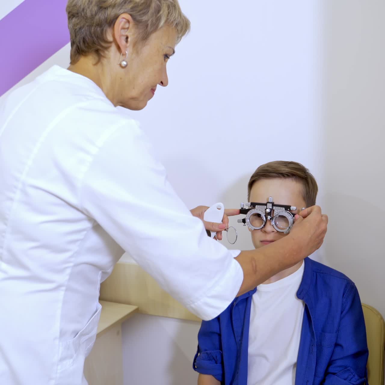 Boy wearing trial set for correcting eye sight. Testing eye sight in clinic. Ophthalmology concept