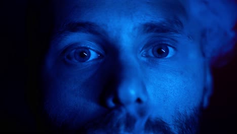 macro close up of male person lighting by blue light smoking cigarette in professional studio - portrait shot