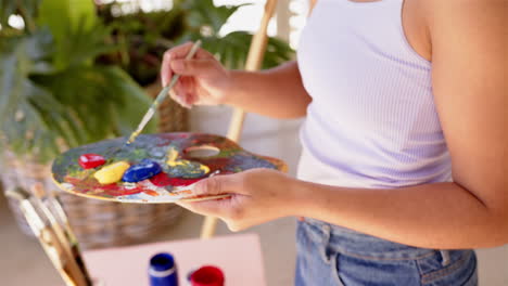 painting on canvas, woman holding palette and brush, creating colorful artwork