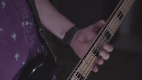 close up view guitarist's fretting hand pressing strings along guitar neck