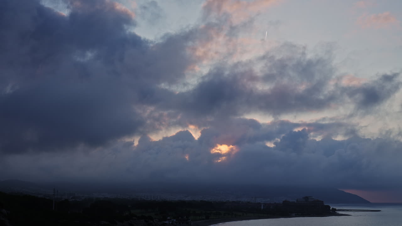 아침 일찍 해가 뜨는 동안 웅장한 산 정상 위에 거대한 비 구름이 형성되면서 매혹적인 타임  ⁇ 스