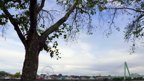 Slow-motion-cinematic-tilt-down-shot-from-the-promenade-on-the-rhine-river-in-cologne-with-a-view-of-a-racing-bike-at-a-festival-and-the-severins-bridge-with-moving-cars