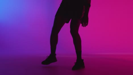 Primer-Plano-Retrato-De-Estudio-De-Un-Jugador-De-Baloncesto-Masculino-Regateando-Y-Rebotando-Una-Pelota-Contra-Un-Fondo-Iluminado-De-Color-Rosa-Y-Azul