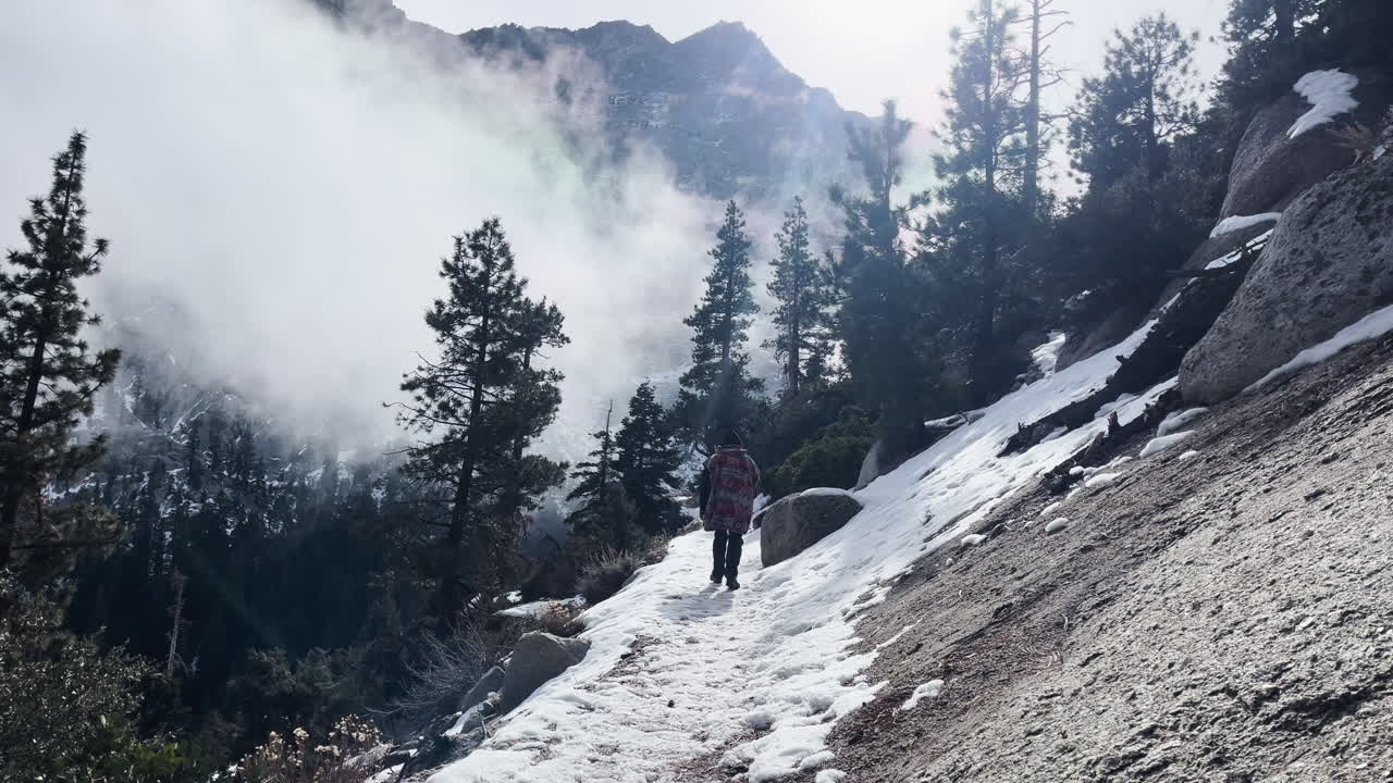 Traveler walking on snowy mountain trail in Alabama Hills, Inyo National Forest, John Muir Wilderness