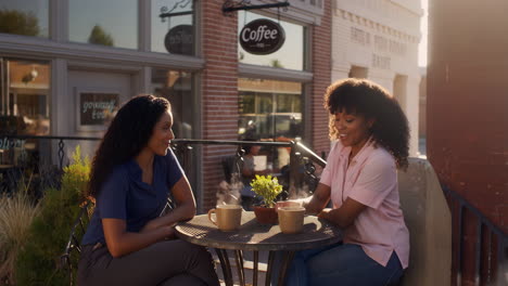 two women enjoying coffee and conversation at an outdoor cafe