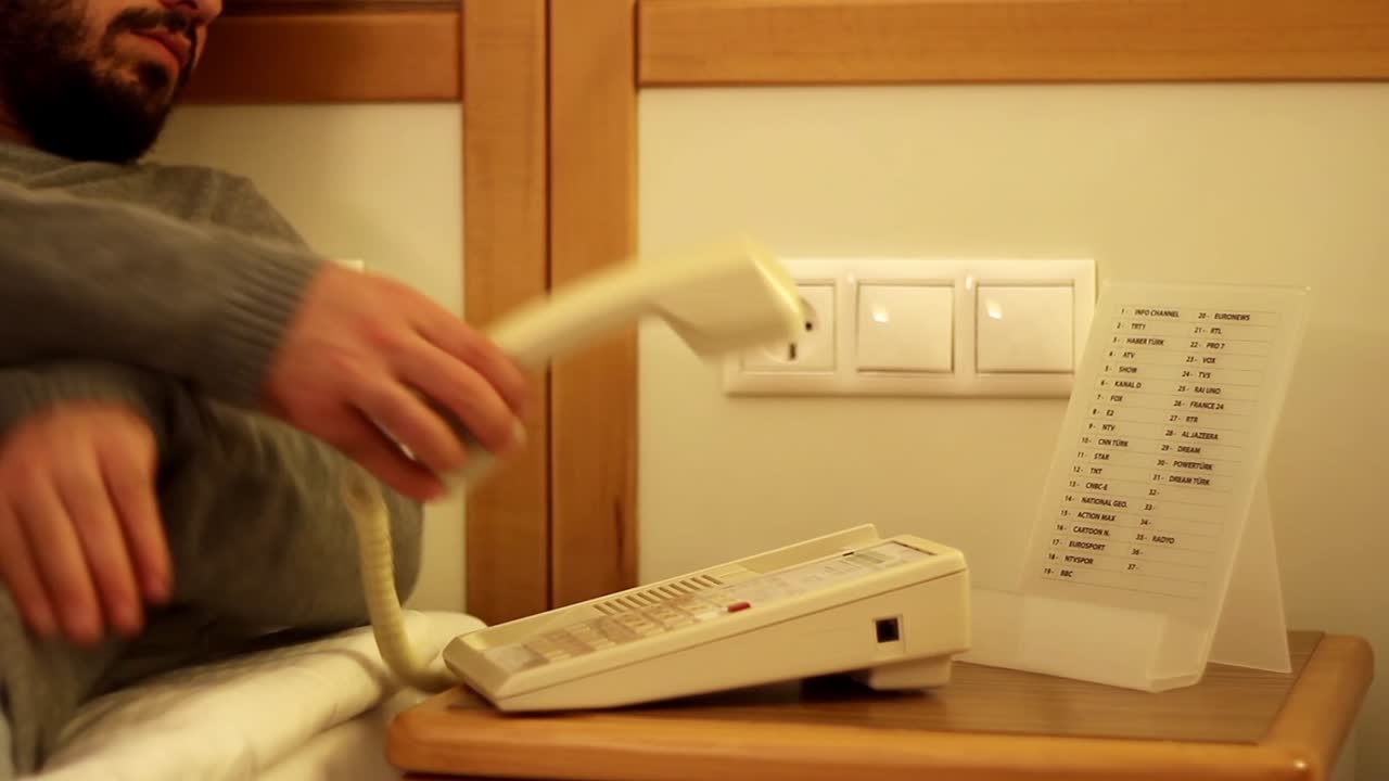 젊은 남자가 리셉션으로 전화하고 있습니다.