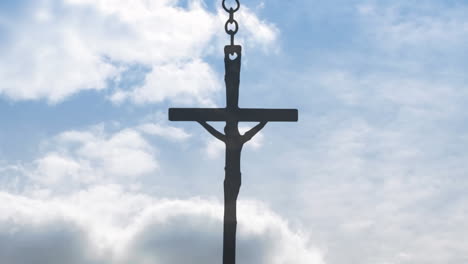 animation of crucifix hanging on chain over clouds moving in blue christmas sky