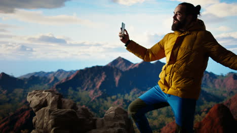 male content creator recording a video surrounded by mountain peaks
