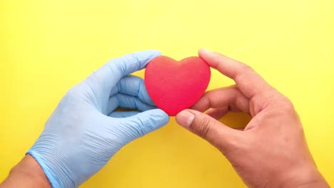 con guantes en las manos sosteniendo un corazón rojo