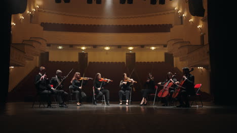 orchestra on scene of opera house four violins two cellos bassoon and flute musicians playing