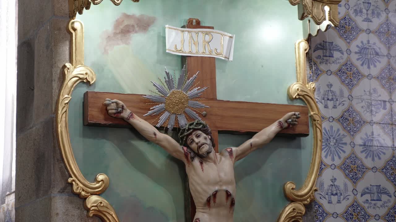 detailed crucifix of Jesus Christ on a wooden cross, framed by gold accents in a church interior