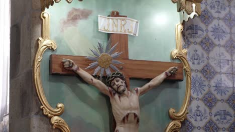 detailed crucifix of jesus christ on a wooden cross, framed by gold accents in a church interior