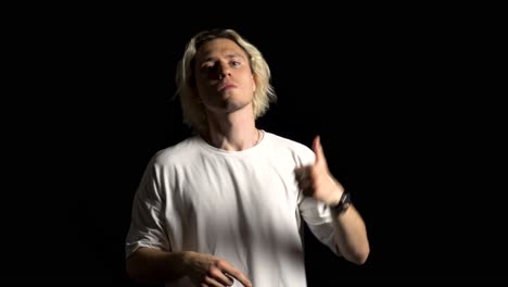 a blond, long-haired man threatens a violence, black background