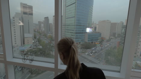 Mujer-Trabajando-En-Negocios-Con-Pad-Junto-A-La-Ventana-Con-Vistas-A-Seúl,-Corea-Del-Sur