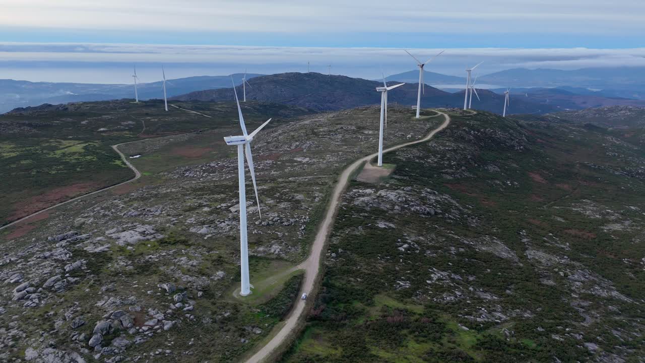 Bil som kör på väg i vindkraftspark för förnybar energi