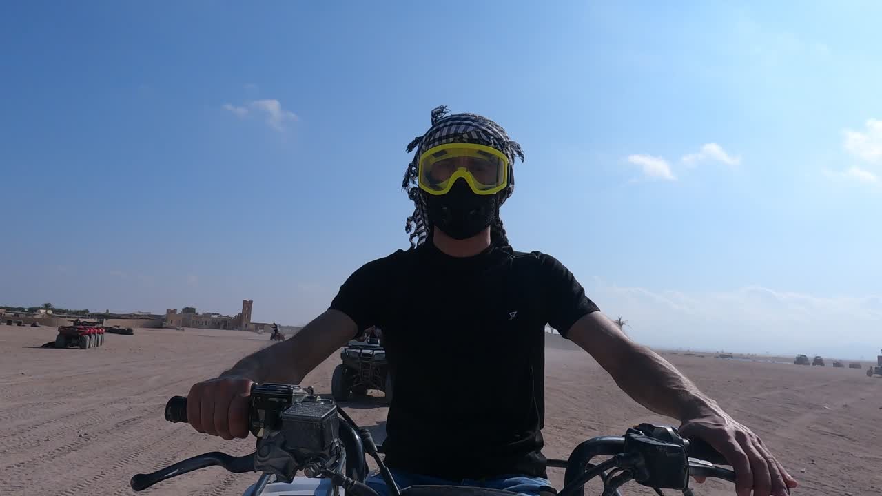 Pria Muda Mengendarai ATV Rekreasi Offroad di Gurun Hurghada Mengenakan Perlengkapan Pelindung Berupa Goggle, Masker Debu, dan Penutup Kepala Arab