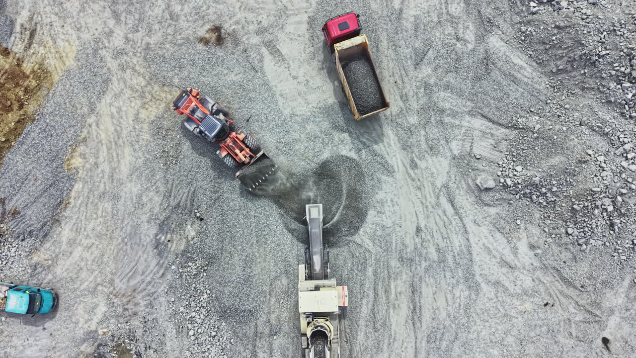 Granite quarry activity with machinery and trucks working on site during daytime