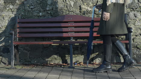 Woman-sits-down-on-street-bench-to-rest-in-sunny-day