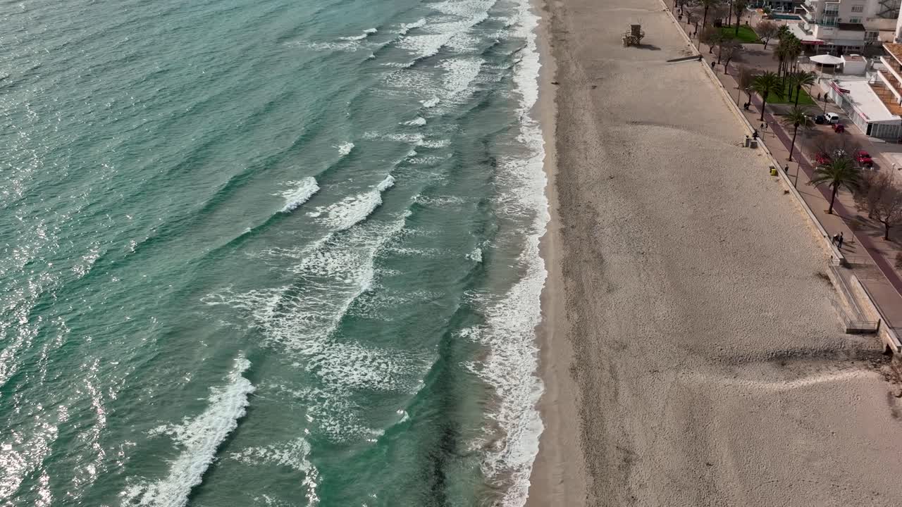 мужчина идет в замедленном темпе по пляжу рядом с волнами в кала миллор, майорка